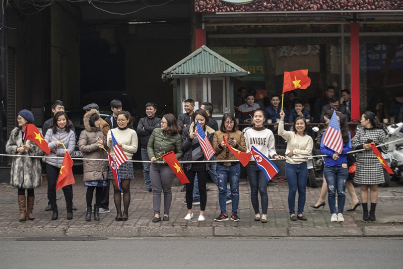 Người dân đứng hai bên đường cầm cờ, chuẩn bị chào mừng Chủ tịch Triều Tiên, Kim Jong-un đến Hà Nội sáng 26.2.2019.